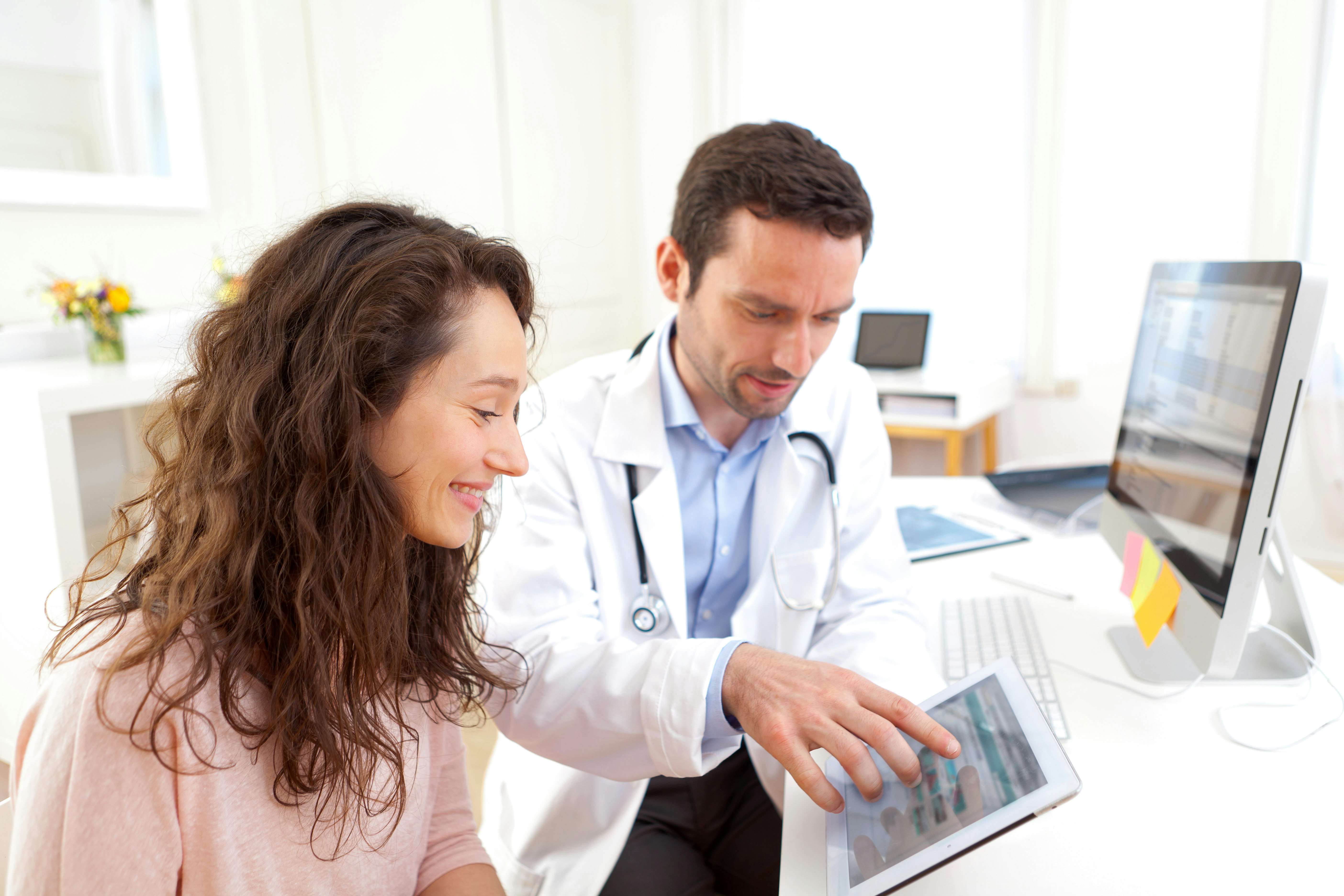 Doctor using computer and tablet to inform patient