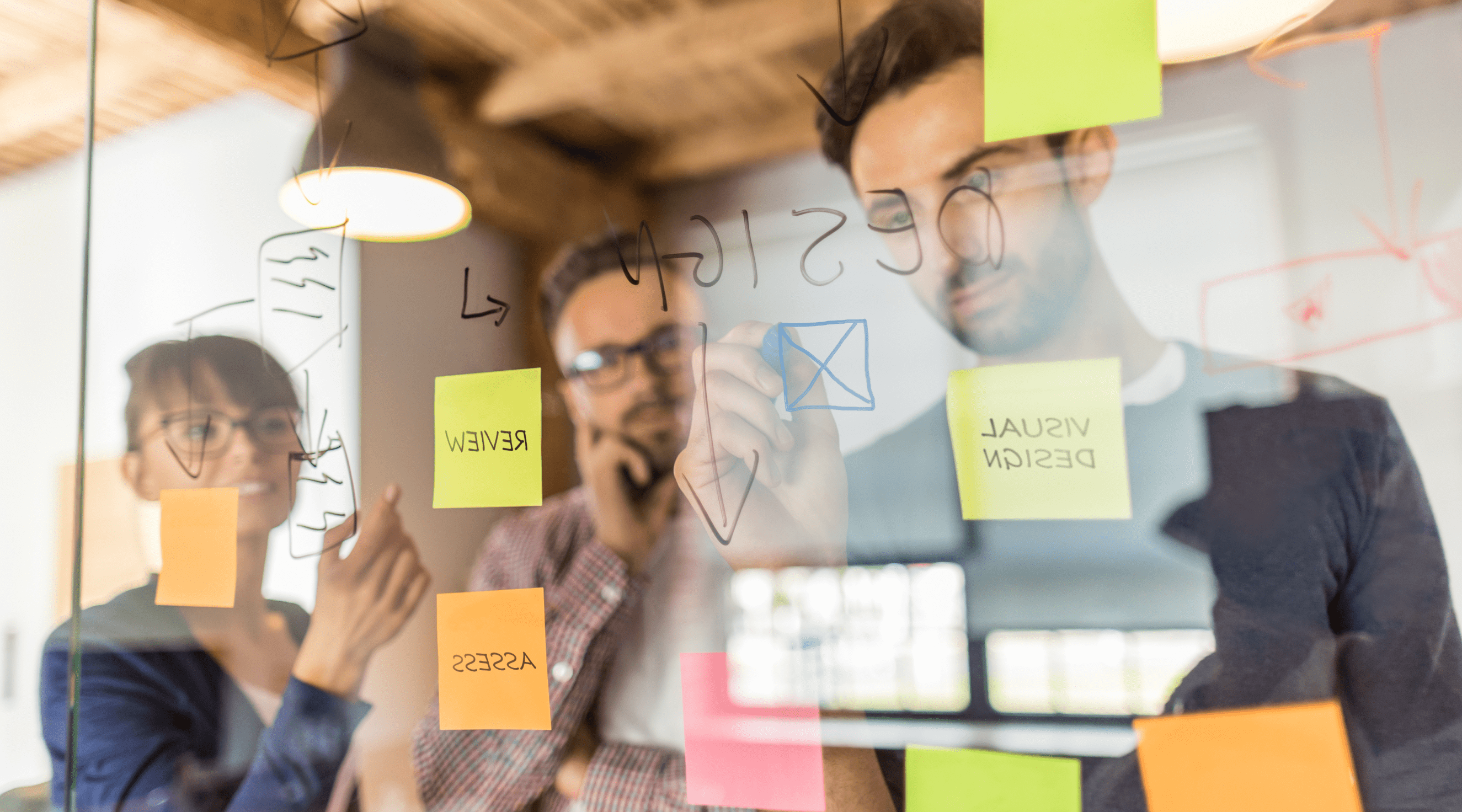 People in design meeting writing on the glass