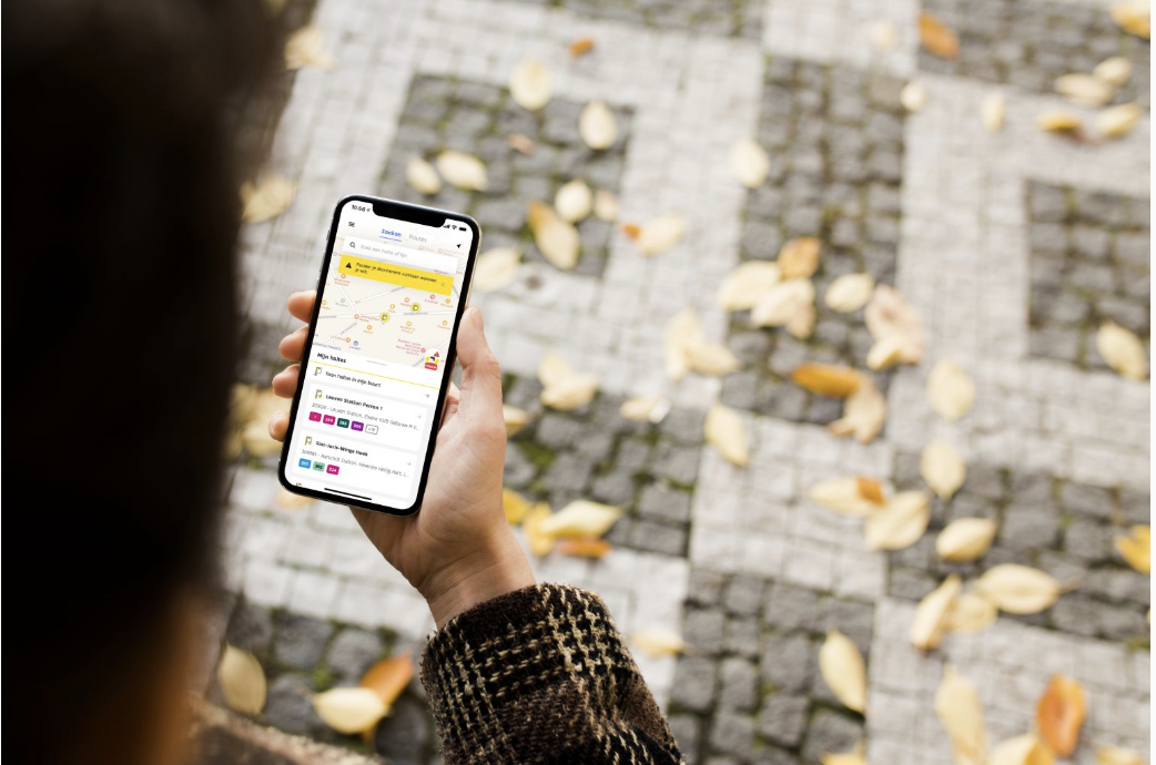 Photo of a person holding a mobile phone with De Lijn's mobile app