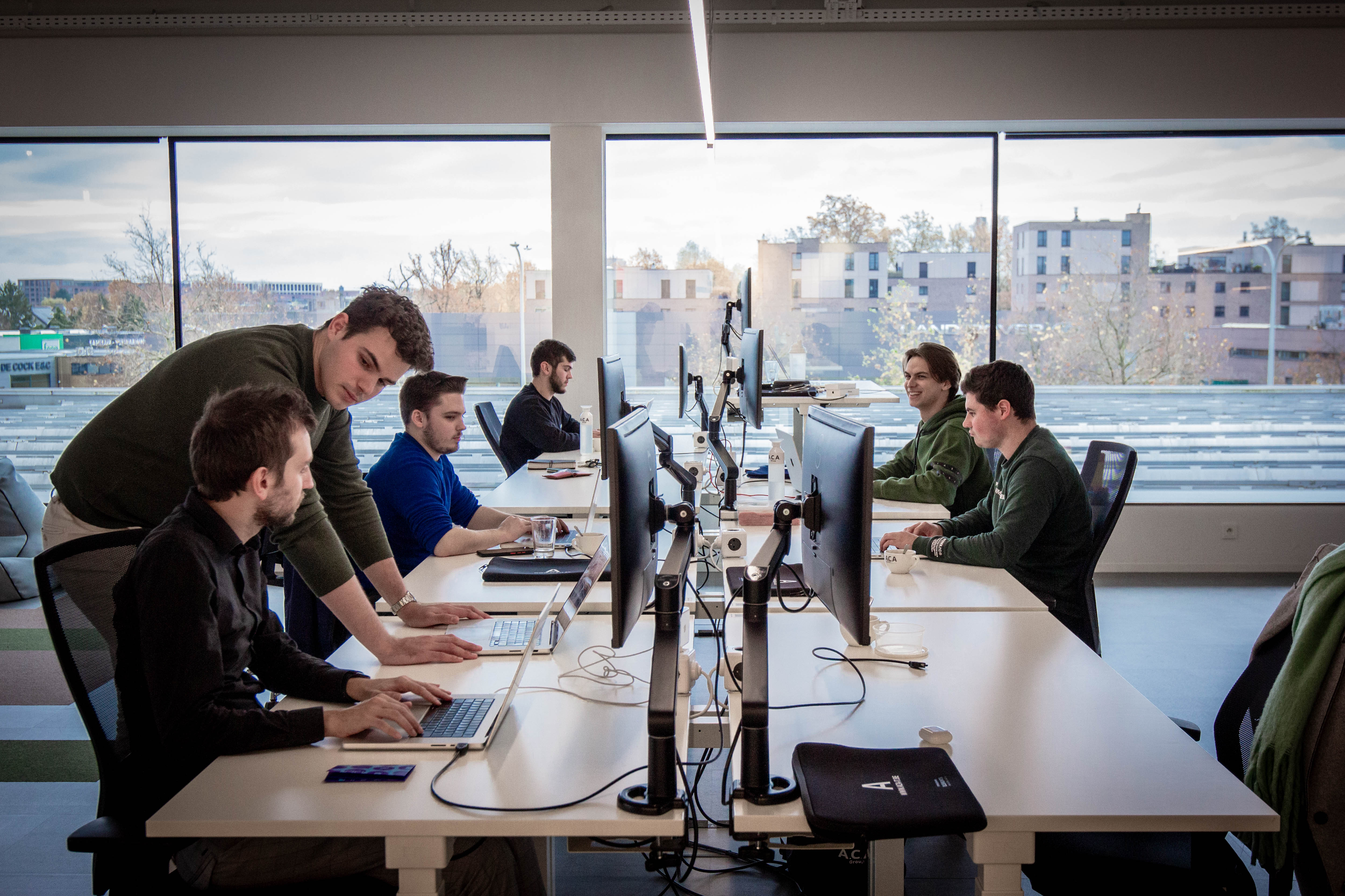 6 men sitting at their desks and working on computers