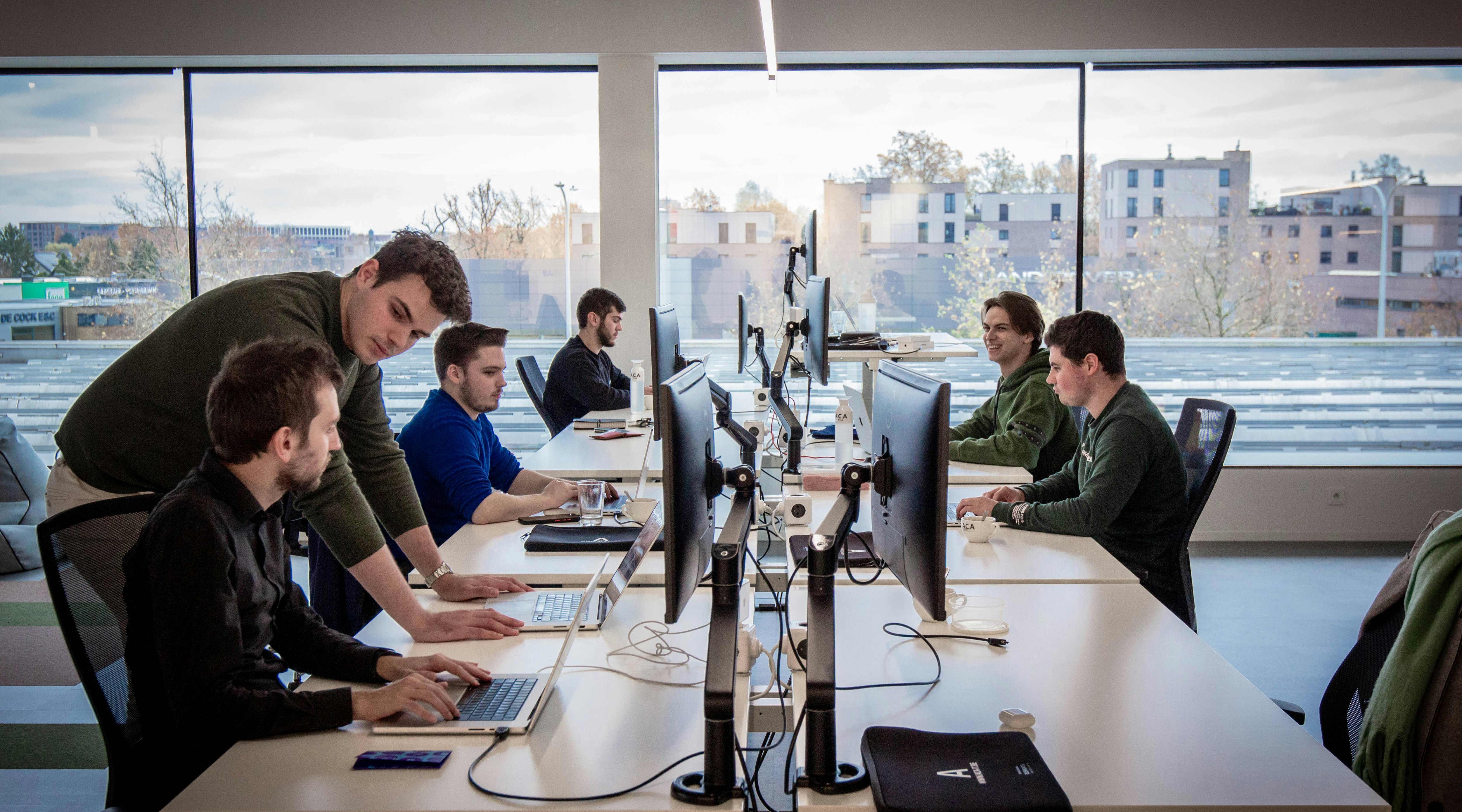 6 men sitting at their desks and working on computers