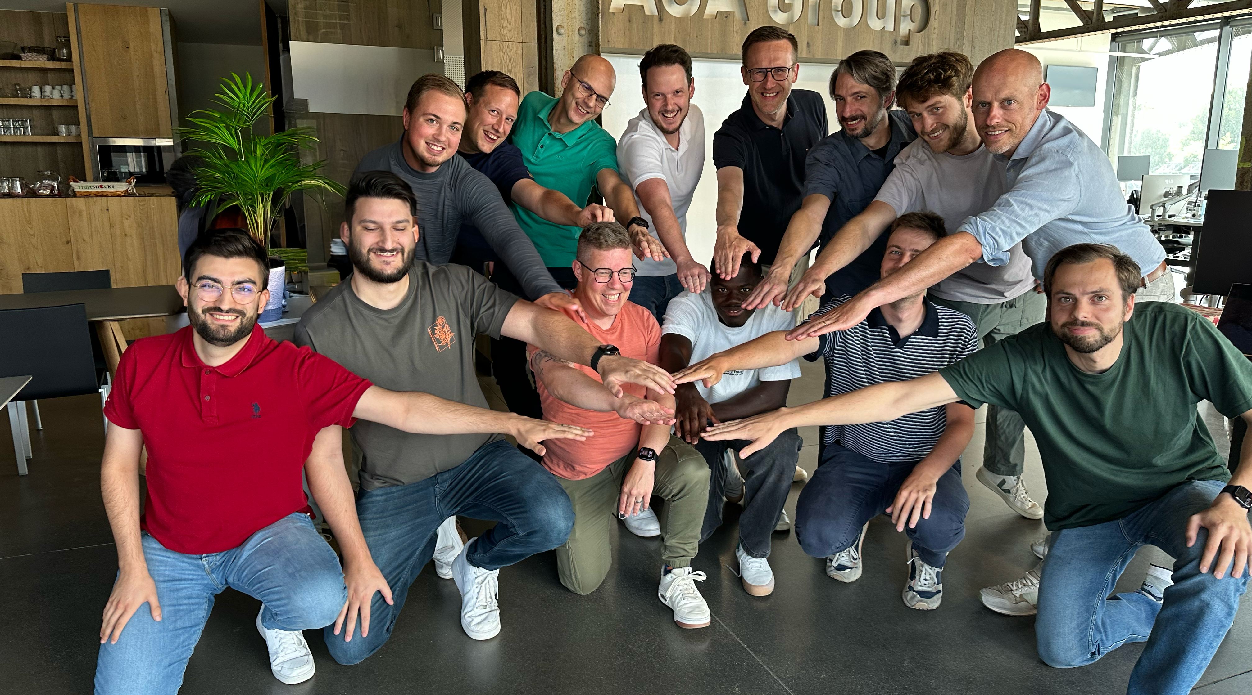 Een team van 14 personen poseert voor foto
