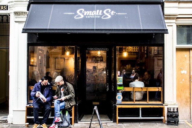 Two men chatting and drinking coffee outside Small Street Espresso.