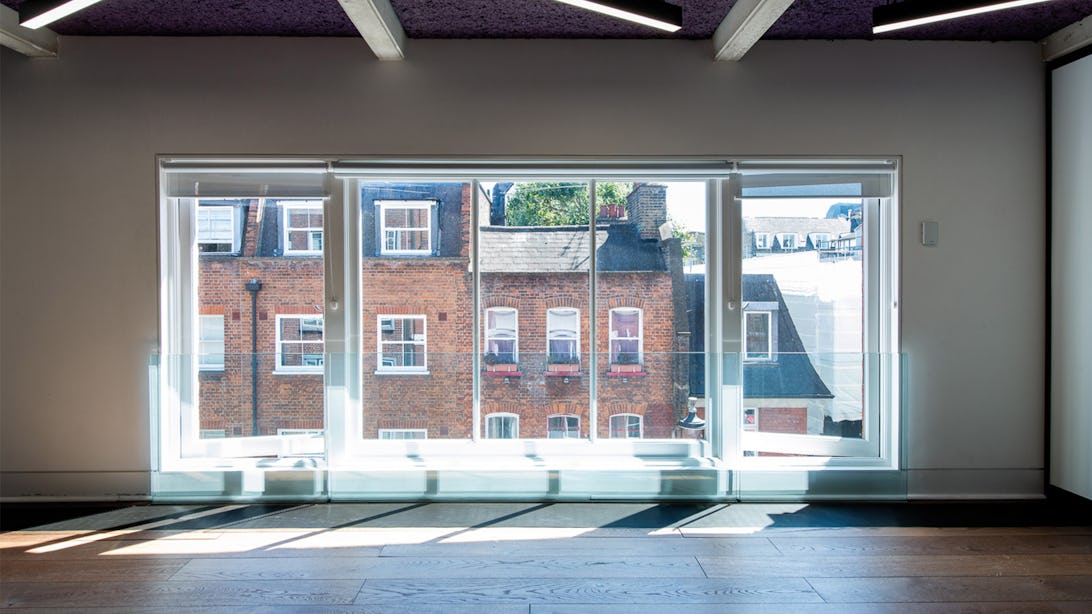 Large windows with lots of natural light shining onto hard wood floors at Runway East Wardour Street