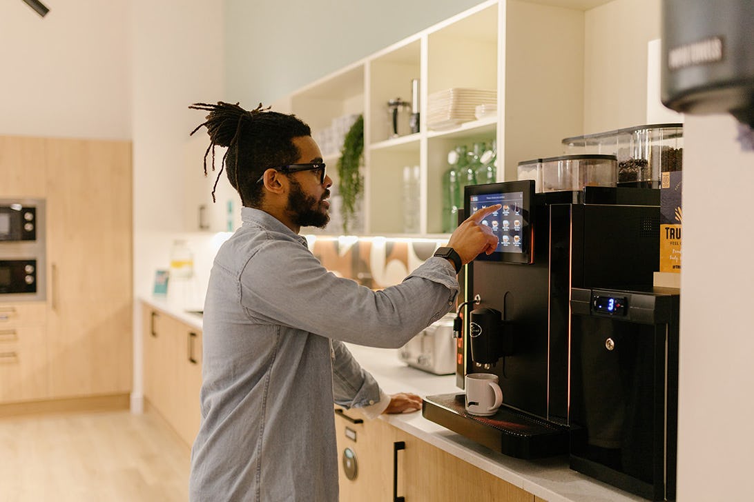 A man using a coffee machine in Runway East Birmingham's coworking space