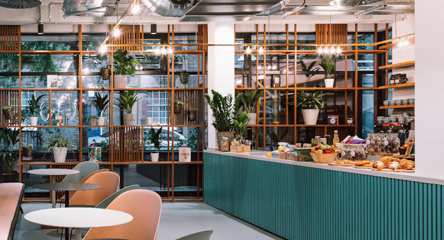 A photo of the cafe with lots of produce at the counter and some tables and chairs.