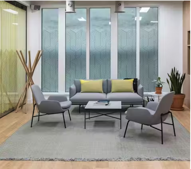 An image of a breakout space, a grey sofa with two arm chairs and a coffee table.