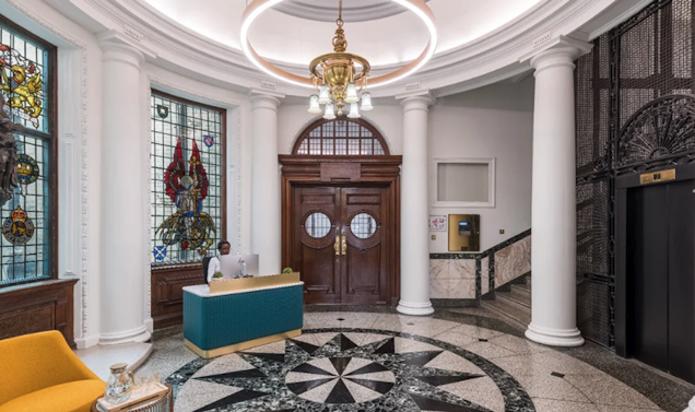 A photo of the grand entrance with stained glass windows and a receptionist at a desk.