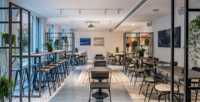 An image of the x+why's breakout space, a mix of benches and smaller cafe style tables.
