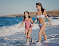 Mother and daughter walking in the surf highlighting mommy makeover in Houston.