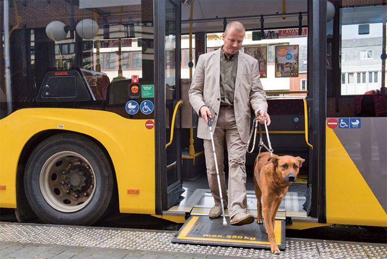 Homme aveugle descendant du bus avec son chien