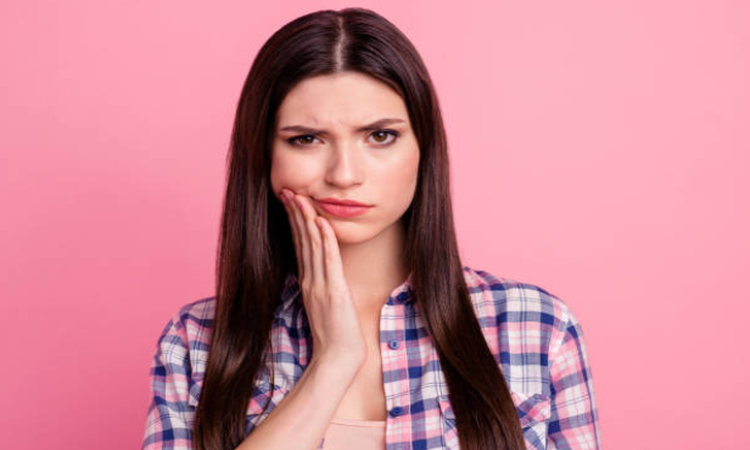 woman holding her jaw in discomfort