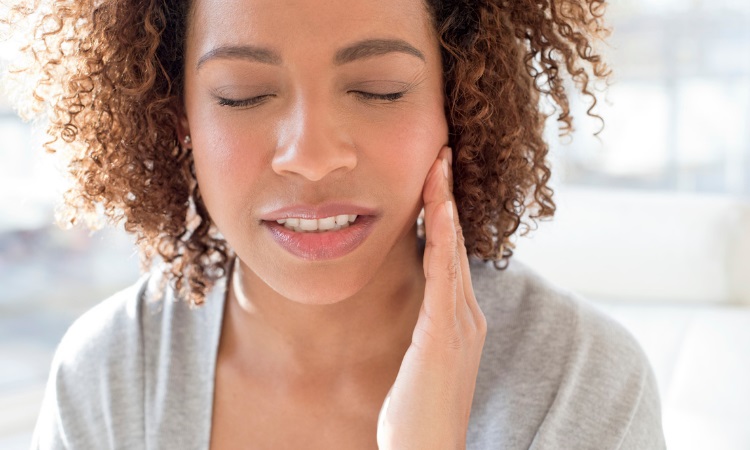 woman holding her jaw in discomfort