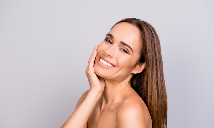 woman smiling while holding her face