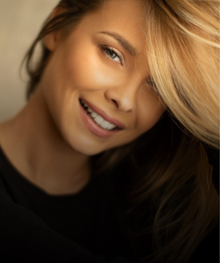 Blonde woman smiling with her hair over some of her face