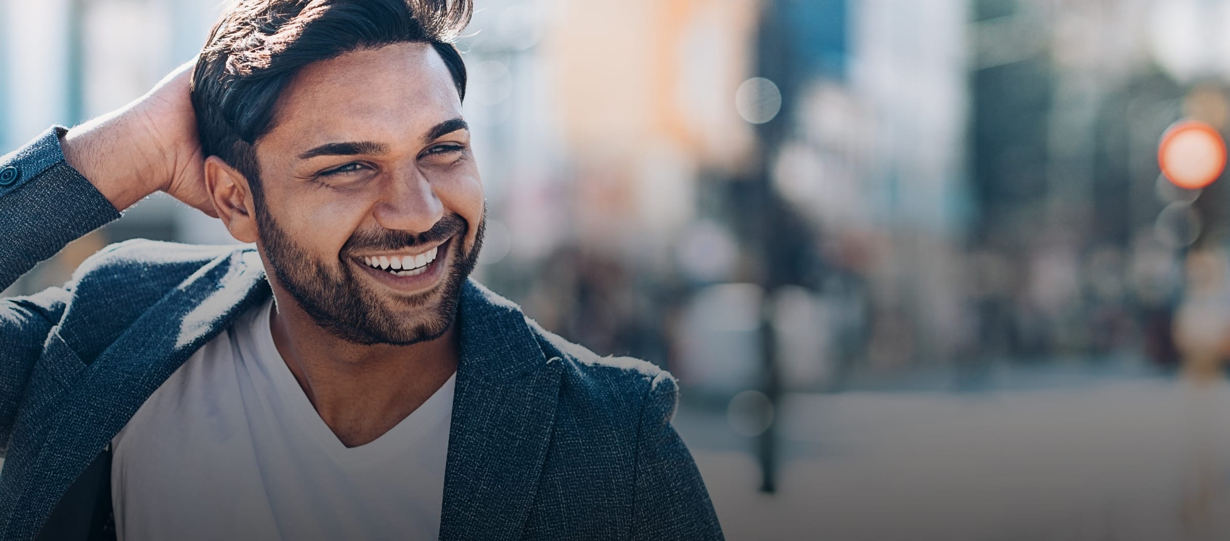 Man smiling outside, running his hand through his hair