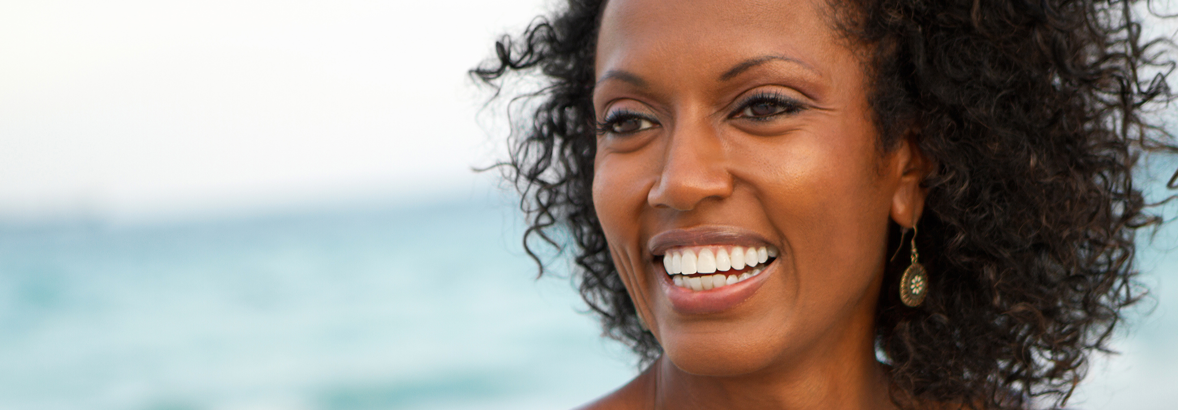 Beautiful woman with curly hair smiling outside