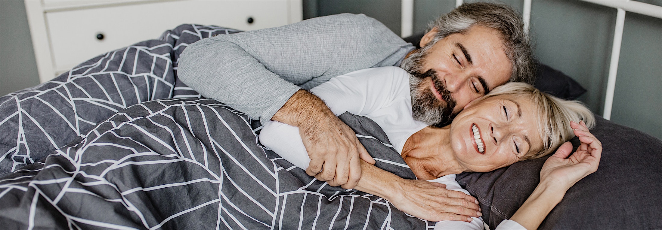 Older couple smiling, laying in bed