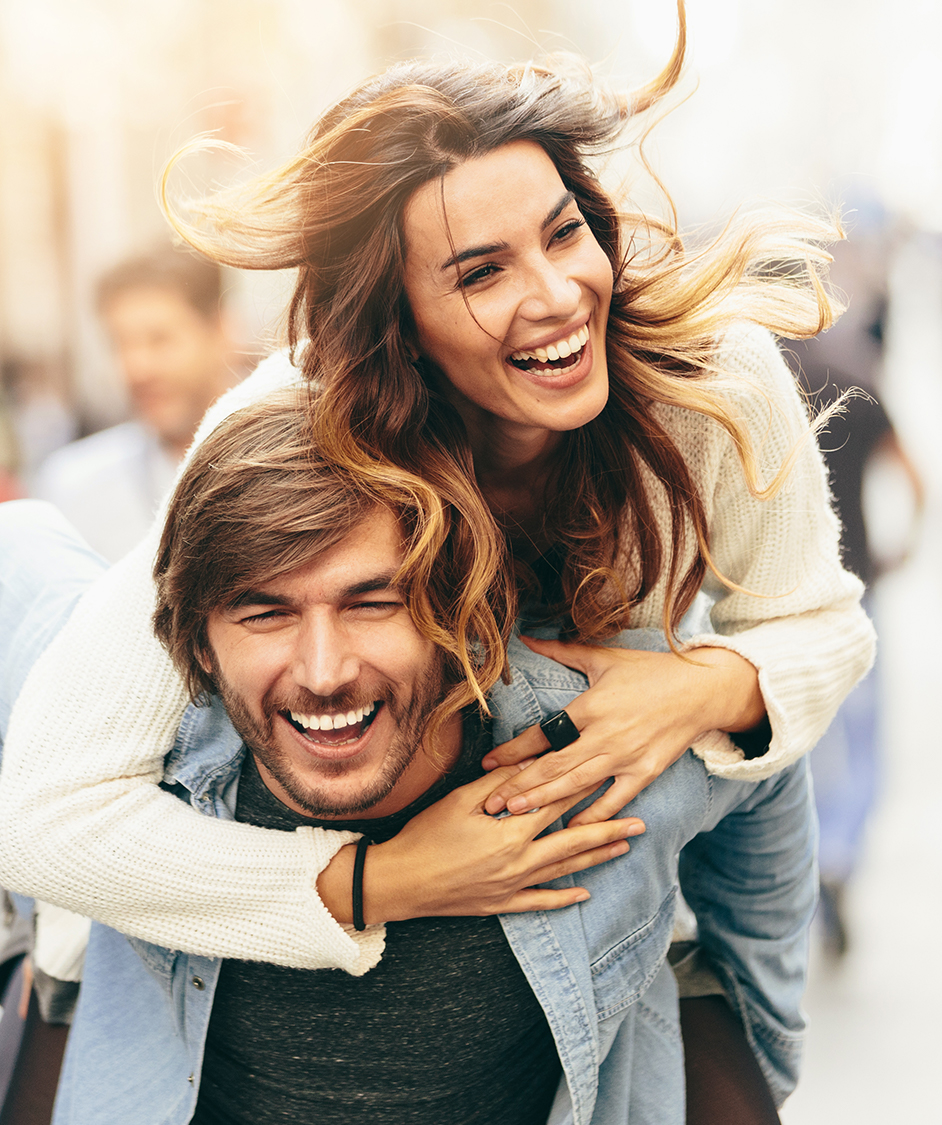 Happy couple laughing while the woman gets a piggy back ride