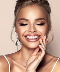 blond woman with white nails and a white top smiling