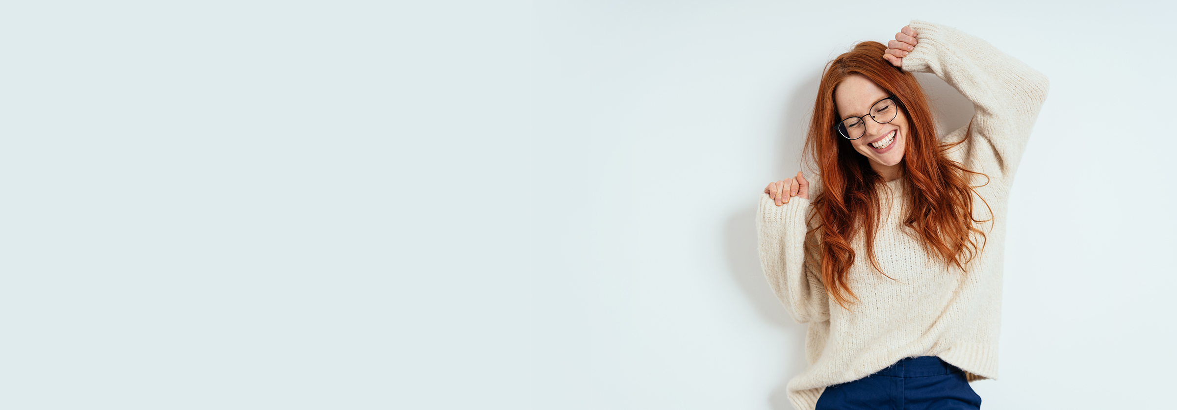 Woman with long red hair smiling with her hands up in the air