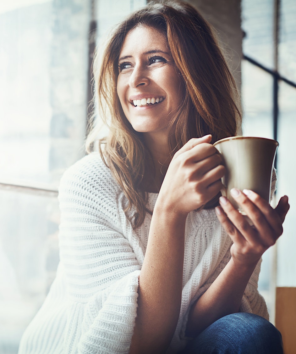 Woman smiling holding a cup of coffee