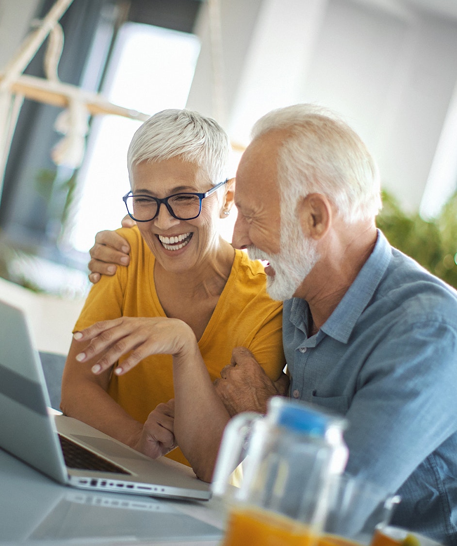 older couple laughing while on a laptop