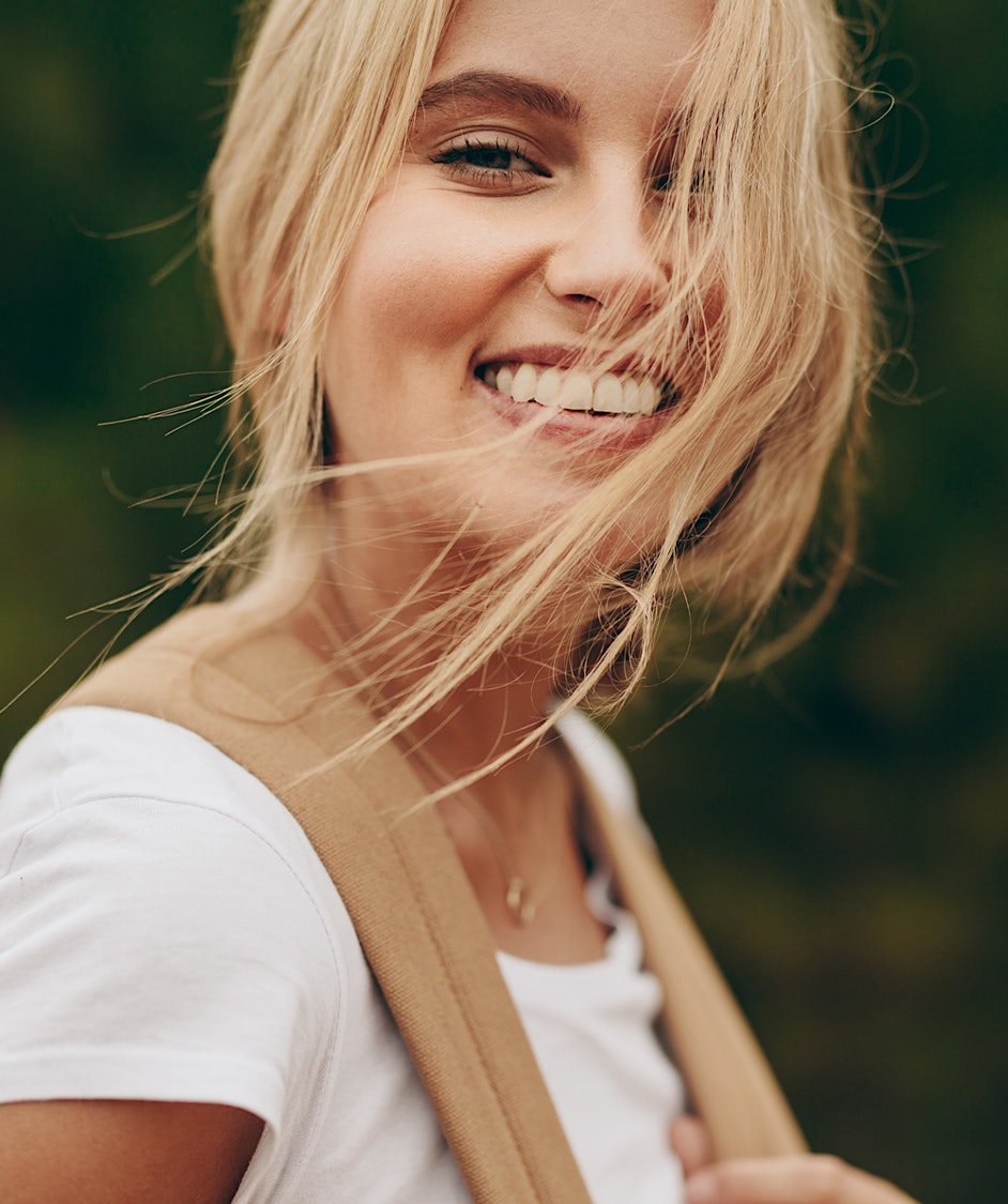 Girl smiling with her blonde hair blowing in her face