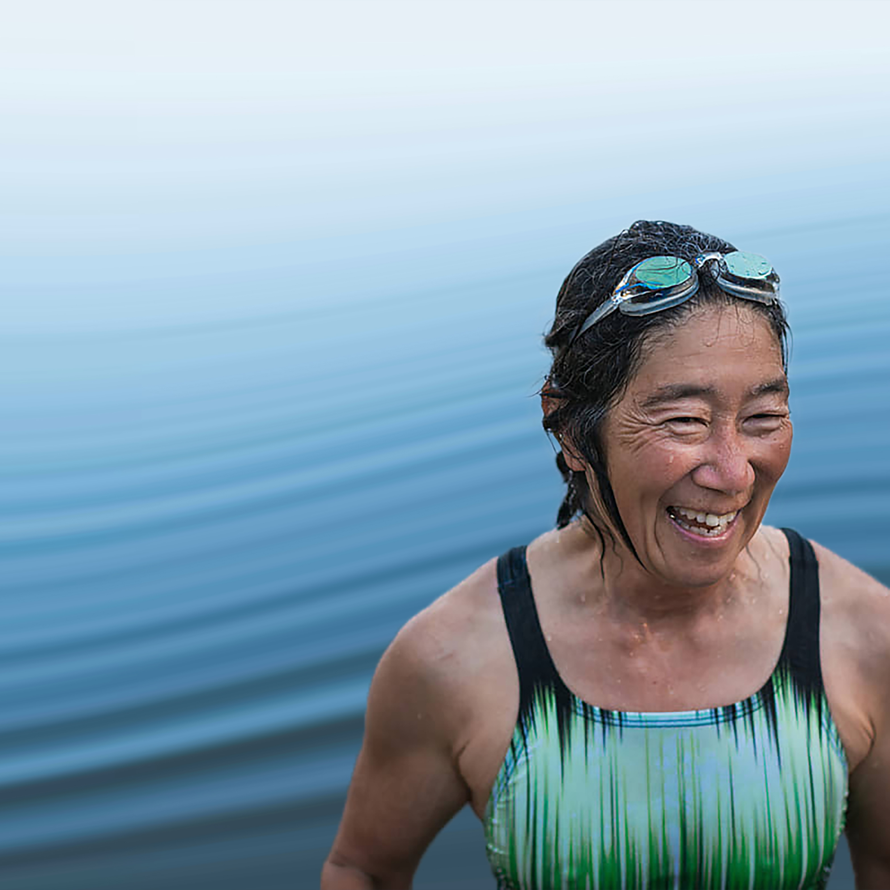 Woman in swimming costume and goggles standing in water