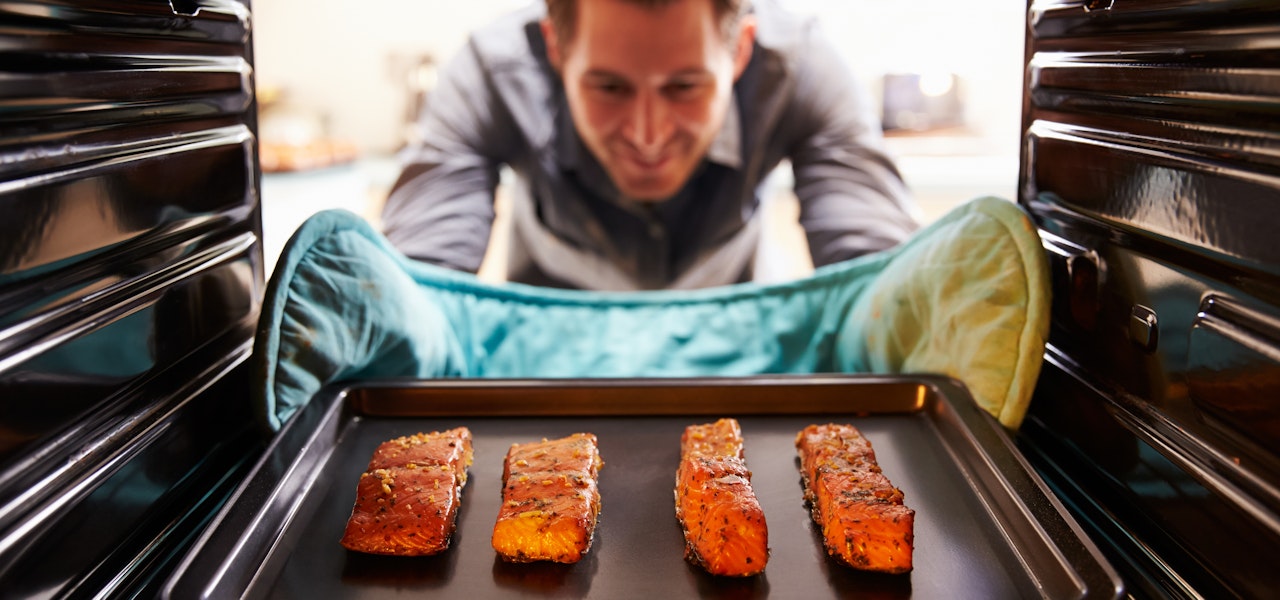 omega-3-benefits-man-taking-salmon-from-oven