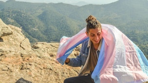 person-on-mountaintop-with-trans-flag