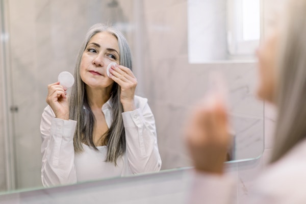someone-using-moisturizer-in-the-mirror