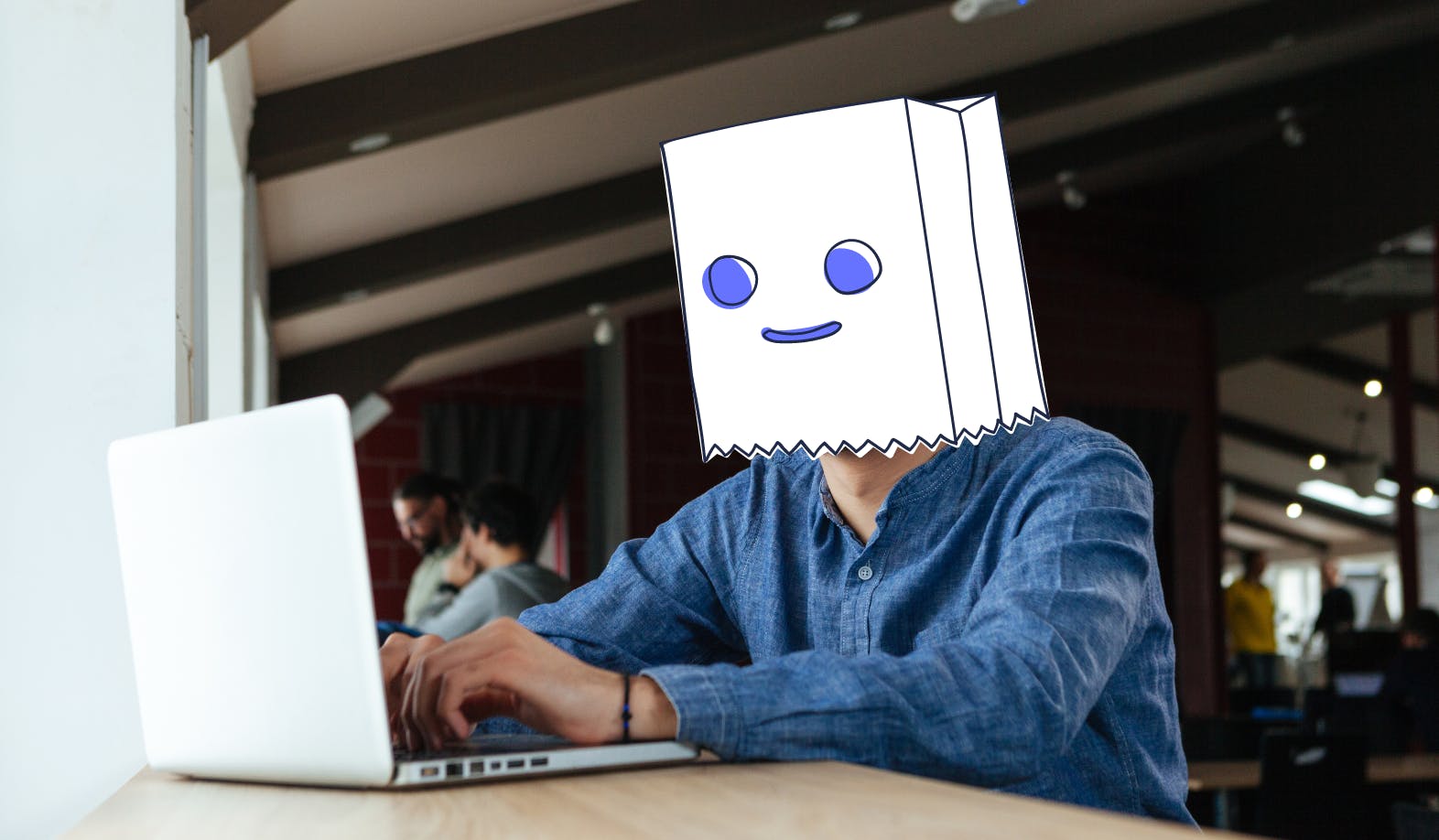 Photographic image of a man behind his laptop. In the StartMail illustration style a paper bag with an illustrated face representing Bagman, representing being anonymous.