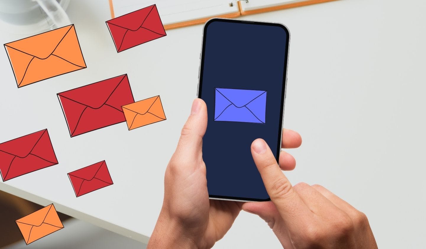 Blog Post Image of hands holding a phone displaying an illustration of a StartMail email envelope that is safe. Next to the phone are floating spam emails in red and orange.