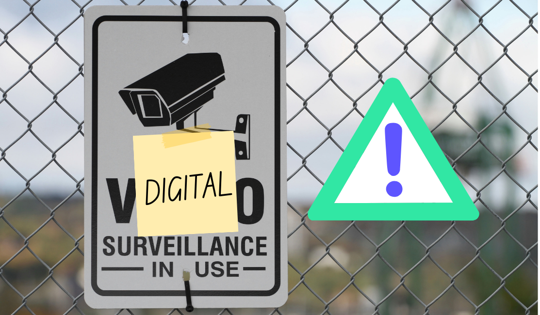 A chain link fence has a warning sign on it with a surveillance camera on it that reads, thanks to a note on top of it, "Digital Surveillance In Use"
