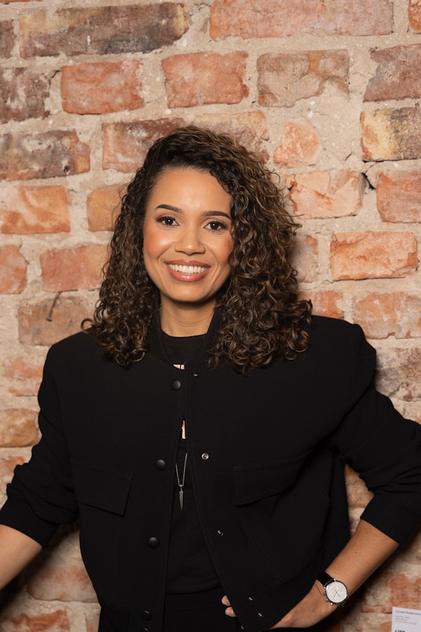 Personal branding headshot with a brick wall backdrop of Alexandra Davis