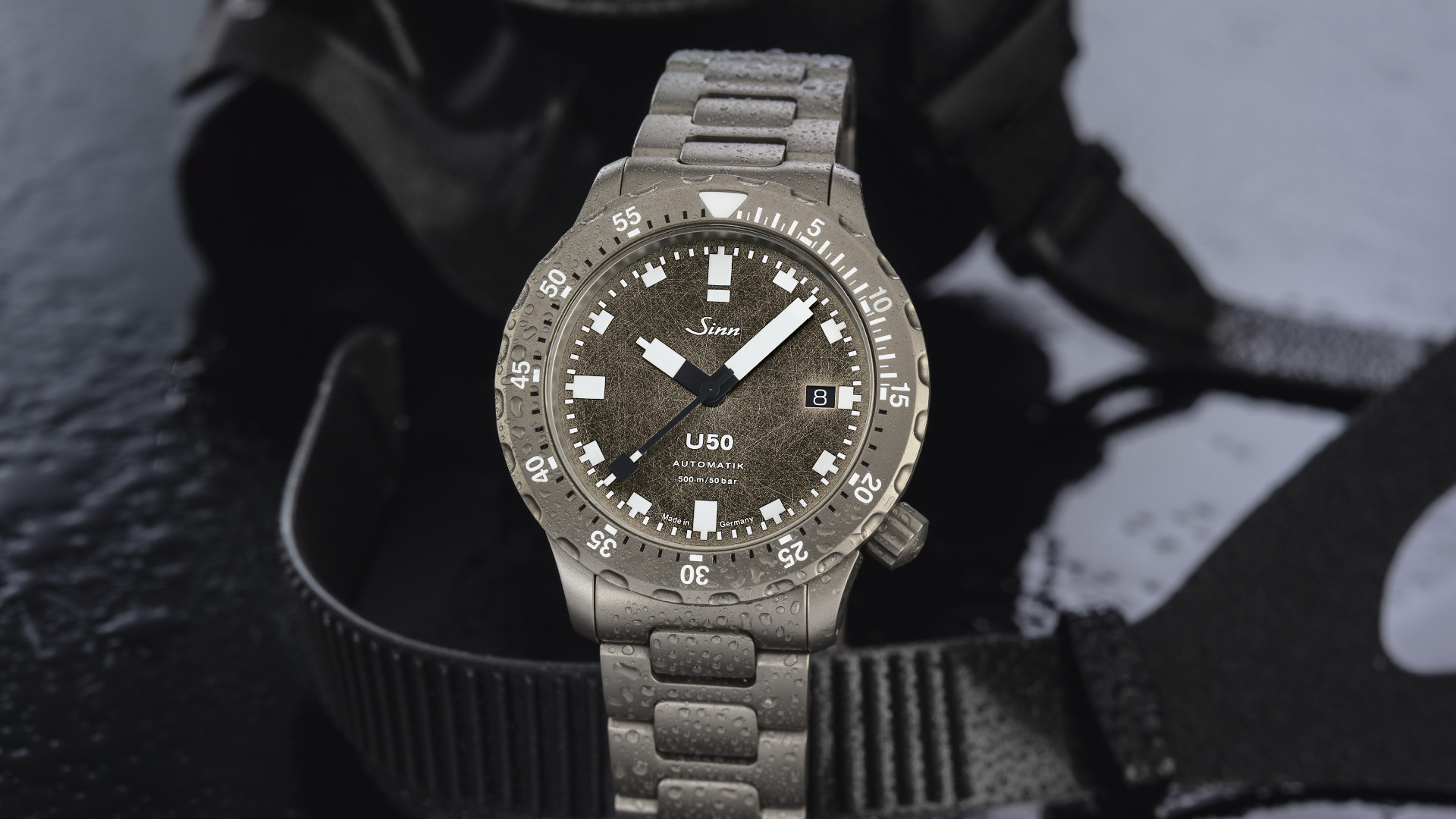 Newsgalerie Sinn T50 mit Dekor-Schliff-Zifferblatt und Stahlarmband auf dunklem Grund