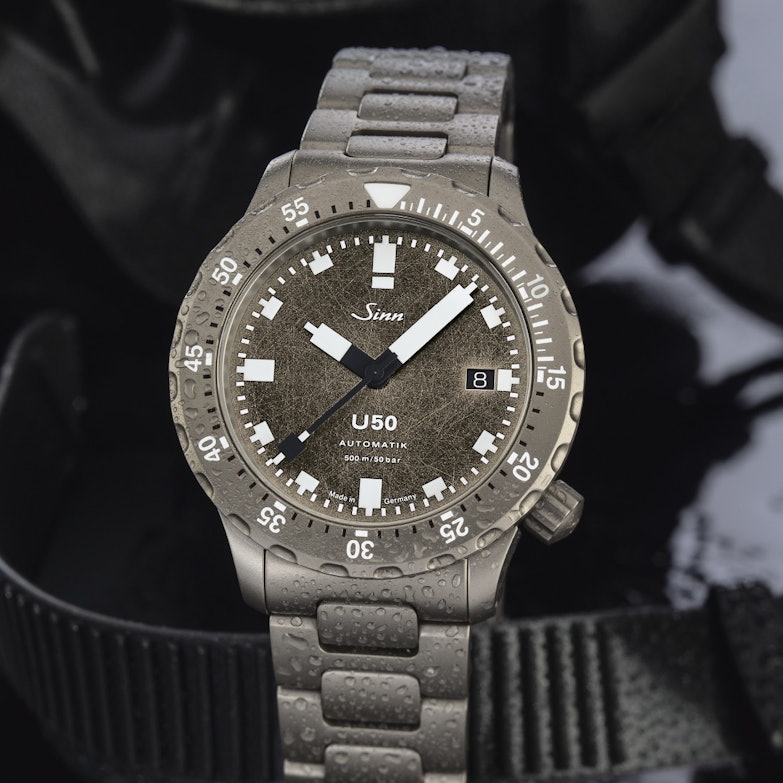 Newsgalerie Sinn T50 mit Dekor-Schliff-Zifferblatt und Stahlarmband auf dunklem Grund