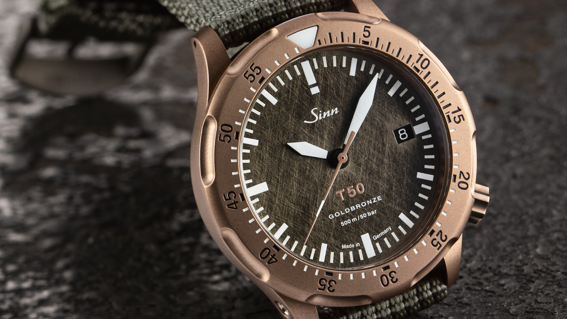 Newsgalerie Sinn T50 Goldbronze mit Bronzegehäuse und Textilband auf Steinboden