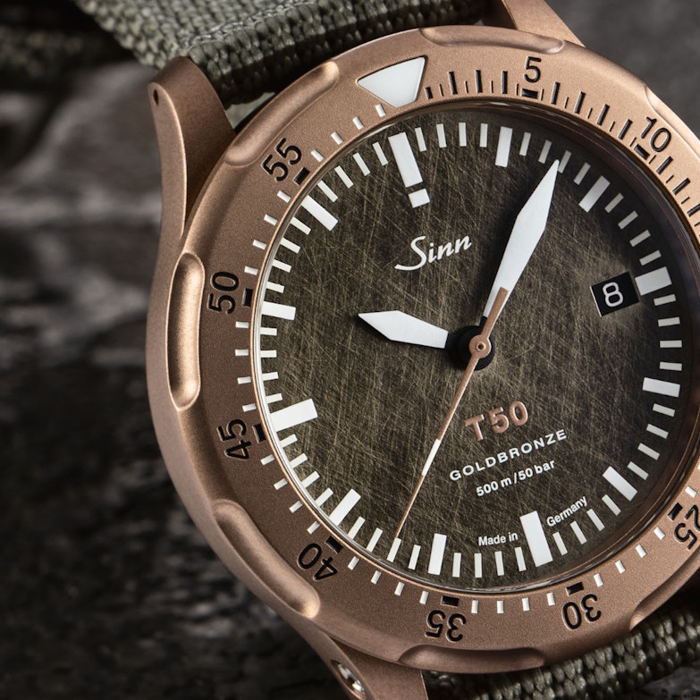 Newsgalerie Sinn T50 Goldbronze mit Bronzegehäuse und Textilband auf Steinboden