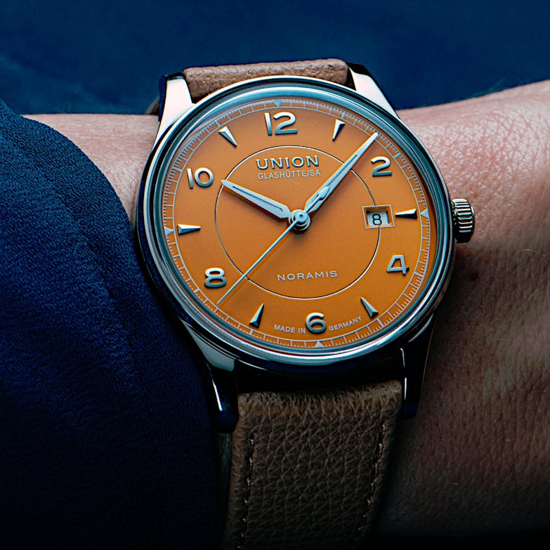 Newsgalerie Union Noramis mit Datum - das Modell mit gelbem Zifferblatt am Handgelenk einer Person