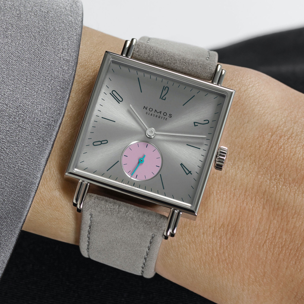 Nomos Tetra Die Unerreichbare - Uhr mit silberfarbenen Zifferblatt und grauen Lederband an einem Handgelenk