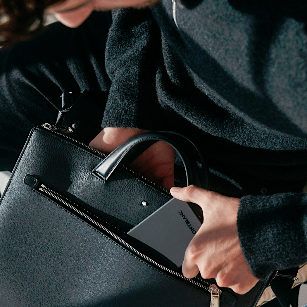 Montblanc Meisterstück 4810 Kollektionsbild - Person die ein Handy in eine schwarze Tasche steckt