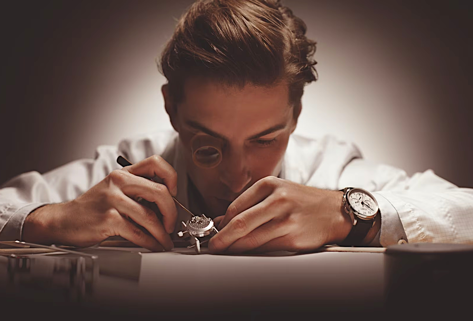 Union Glashütte Detailbild 1 - Uhrmacher bei der Arbeit vor einem dunklen Hintergrund