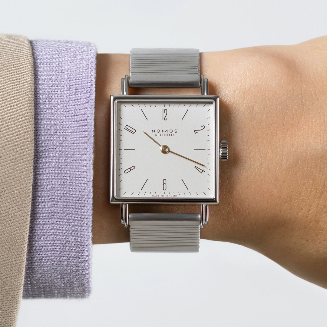 Nomos Tetra Die Kapriziöse - Uhr mit cremefarbenen Zifferblatt und grauen Lederband an einem Handgelenk