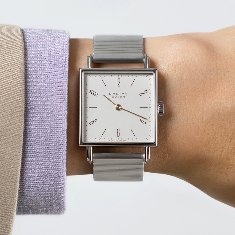 Nomos Tetra Die Kapriziöse - Uhr mit cremefarbenen Zifferblatt und grauen Lederband an einem Handgelenk