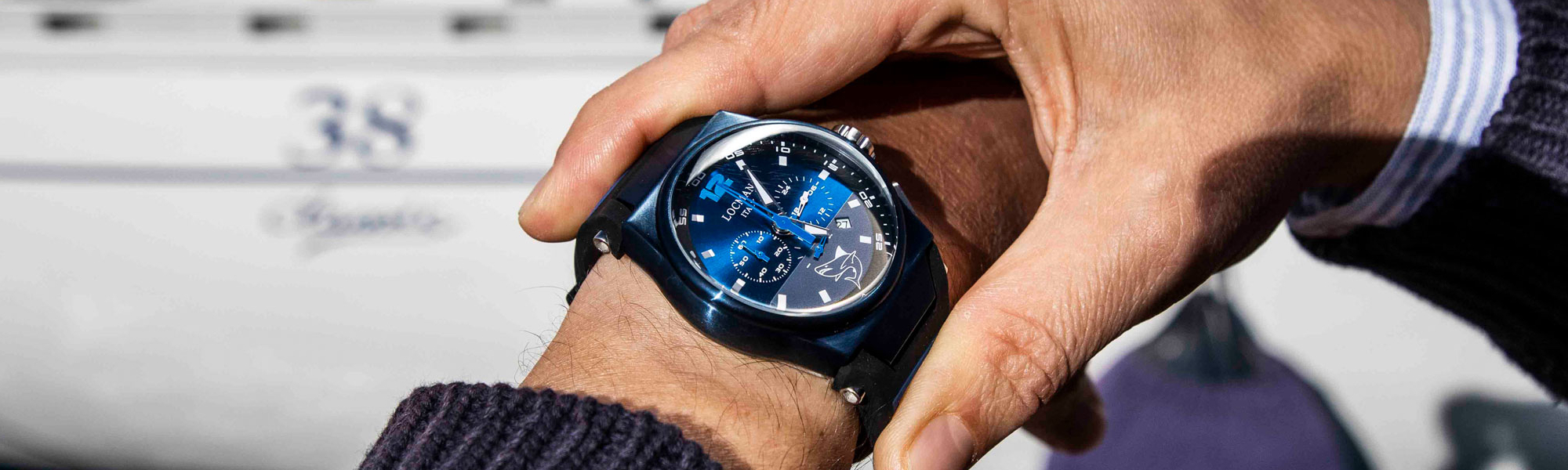 Locman Markenbanner - Mare Modell am Handgelenk eines Mannes vor einem grauen Hintergrund