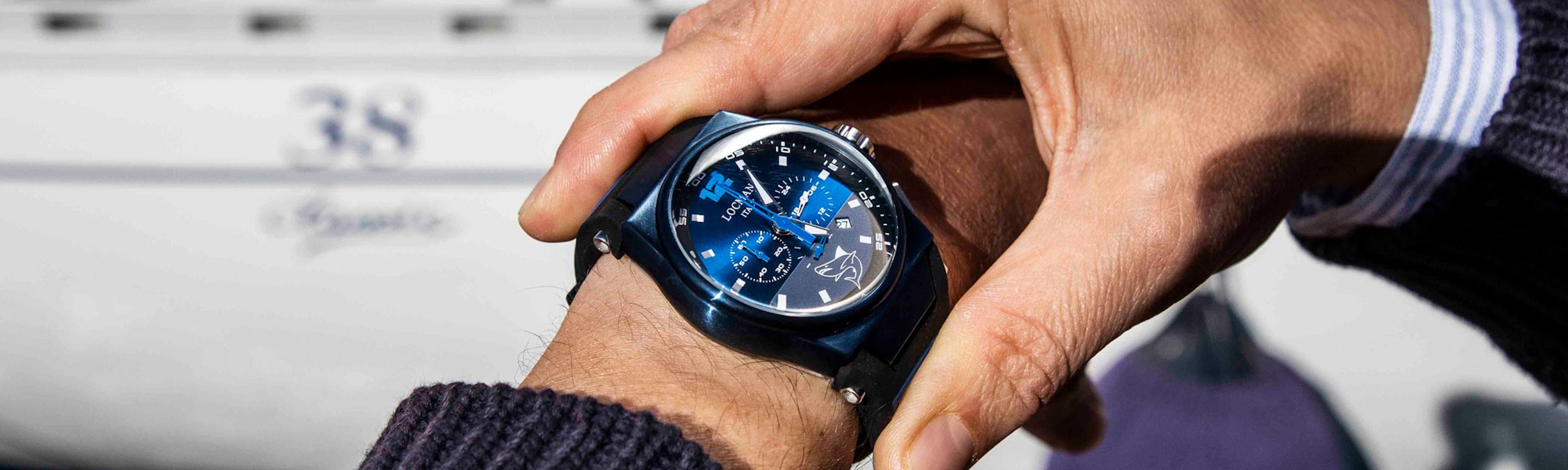 Locman Markenbanner - Mare Modell am Handgelenk eines Mannes vor einem grauen Hintergrund