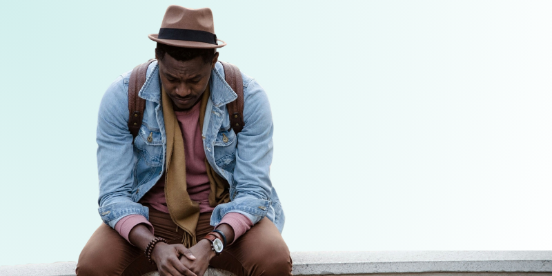 Man sitting with head down, looking overwhelmed and stuck, representing the emotional weight of procrastination.