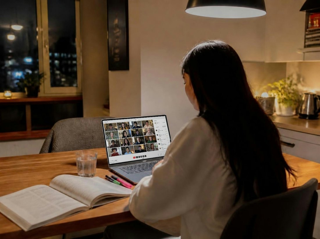 Someone at their kitchen table in the evening, working with a FLOWN session open on their laptop
